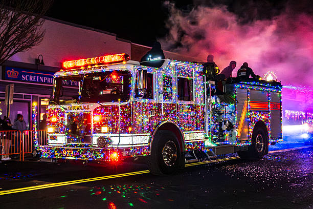 Suffern, NY - US - Dec 6, 2025 A Totowa, NJ fire engine covered in vibrant Christmas lights drives through the Suffern Holiday Parade as smoke and colors fill the night.