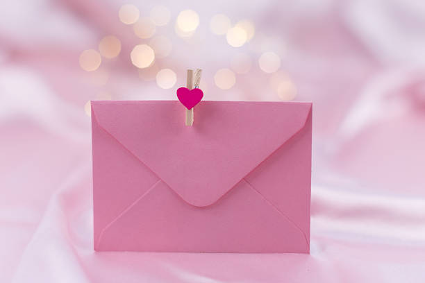 Pink envelope with heart clip on light pink background with bokeh lights. High quality photo