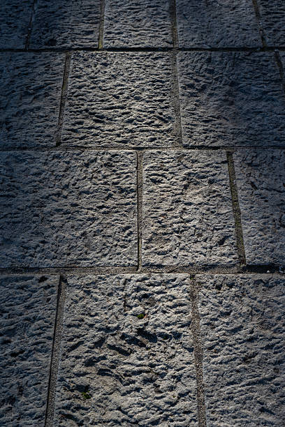 istock A close-up of a textured stone wall illuminated by soft, angled light. The shadows cast on the stone highlight depth and detail. 2250604938