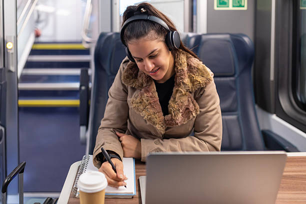 istock Woman commuting on train studying with laptop and coffee 2250605077