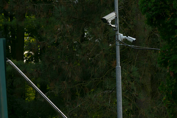 A group of white surveillance cameras installed on a tall metal pole, monitoring different directions. The setup highlights modern security measures and urban surveillance technology.