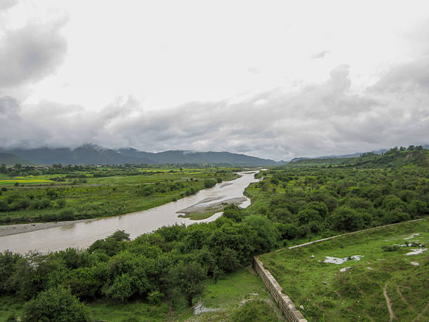 istock Scenic view of a river flowing through lush green fields under cloudy sky 2250615472