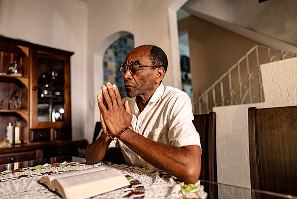 An elderly woman holds her hands together and prays