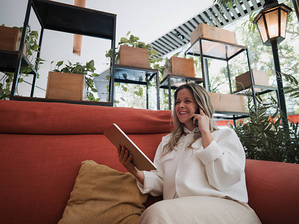 istock Smiling businesswoman using digital tablet while talking on phone 2250618330