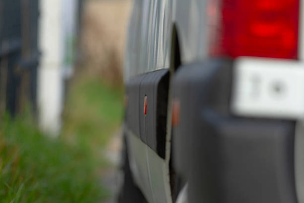 blurred van side and taillight foreground, shallow depth of field capturing wet panel and soft bokeh background, atmospheric urban parking scene, fleet vehicle readiness with subtle reflections