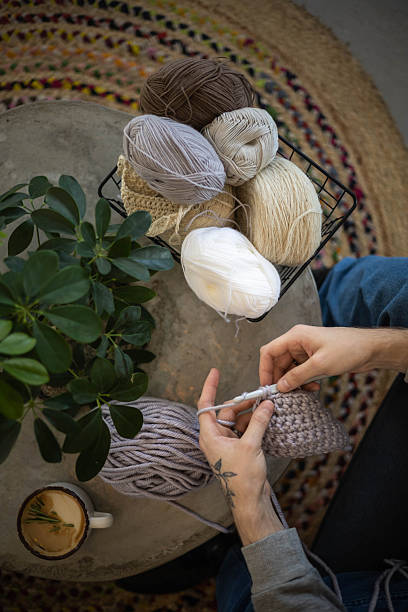 istock Male hands crochet handmade artwork use wool yarn and hook over table with coffee top view 2250626512