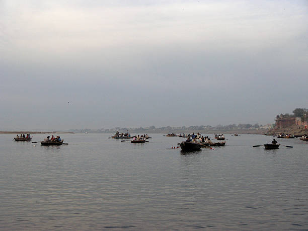 Crowds gather along the Ganges River at a historic ghat in Varanasi - India, engaging in daily rituals, bathing, and communal life. A vibrant scene of tradition, spirituality, and cultural heritage unfolds on the riverbanks.