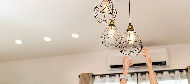 istock Hands reaching ceiling pendant light bulbs modern interior design lighting home decoration energy concept 2250630244