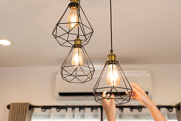 istock Hands adjusting pendant light bulbs modern home interior lighting decoration energy design idea stylish living 2250630246