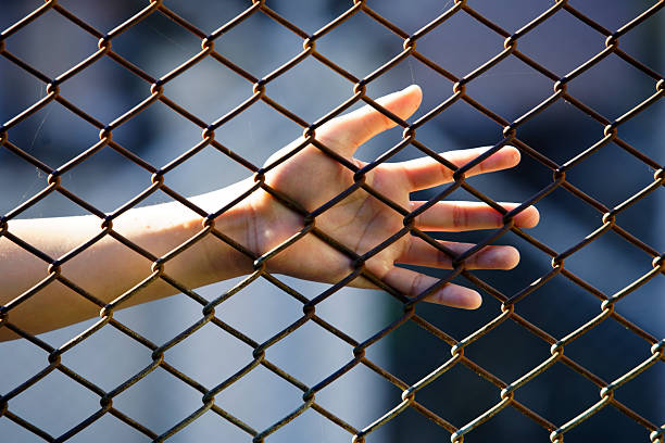 istock Hand Reaching Through Metal Fence with Rusty Chain Links 2250630454