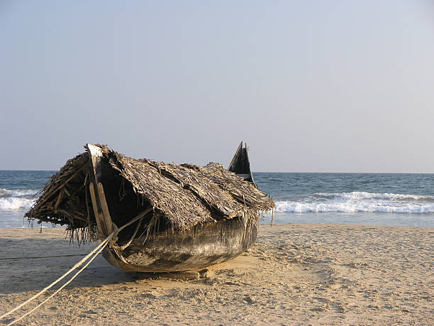 Traditional fishing boats in Kerala - India. The scene reflects coastal resourcefulness and local methods of sun protection, set against a tranquil ocean backdrop.