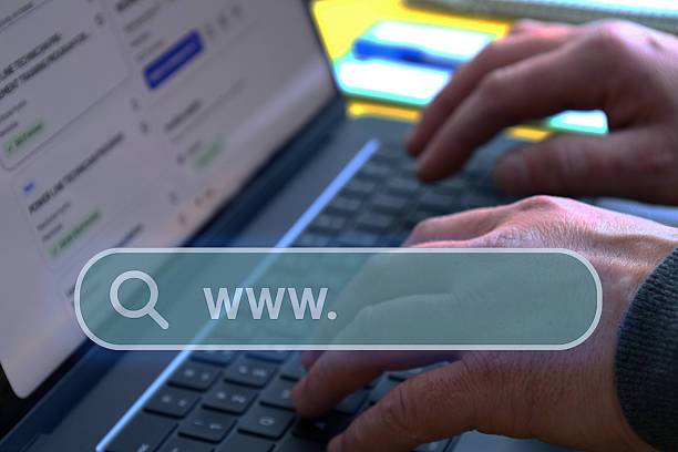 Close-up of hands typing on a laptop with illuminated search bar overlay and www icon symbolizing internet browsing, online research and digital information access.