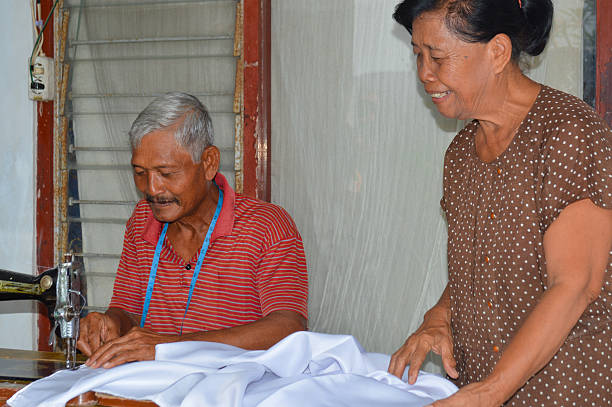 istock Elderly Couple Sewing White Fabric on a Vintage Machine 2250640212