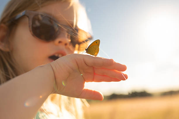 Little girl watching a butterfly on her hand.
