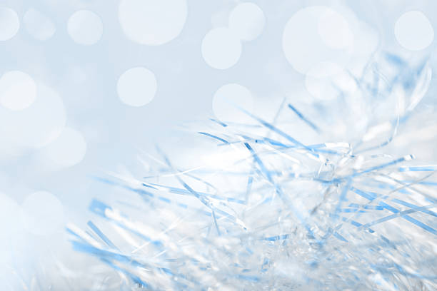Shimmering tinsel strands close-up. The background features soft, blurred  lights that enhance the festive atmosphere. Nice bokeh, space for copy.