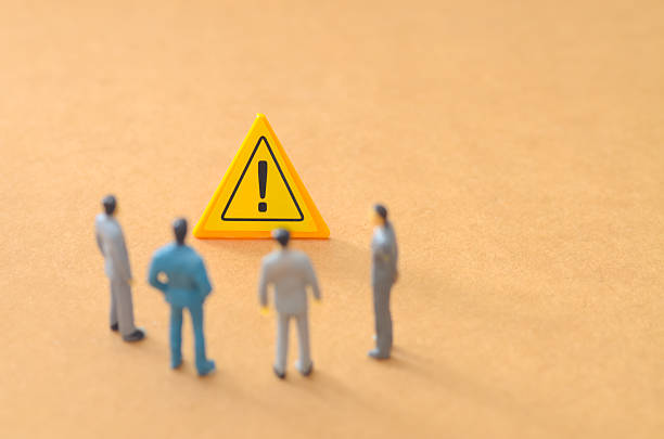 istock Miniature Business Team Analyzing a Yellow Warning Sign and Discussing Risk Management 2250650592