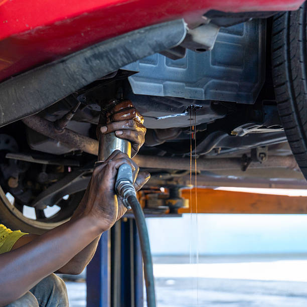 Auto mechanic draining transmission fluid from a vehicle during an ATF or Automatic Transmission Fluid oil change.