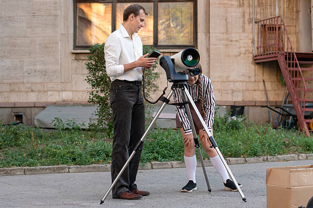 istock Student looking through telescope while teacher supervises outdoors 2250652667
