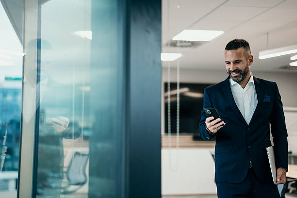 istock Busy businessman walking in modern office checking smartphone 2250654759