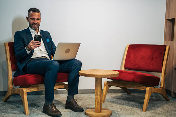 istock Businessman multitasking with smartphone and laptop in office lounge 2250656298