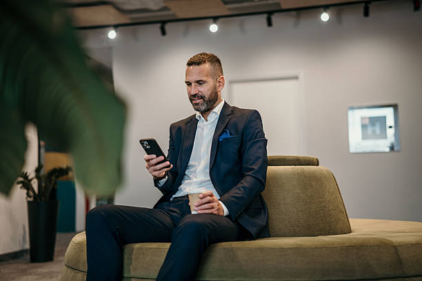 istock Businessman networking on phone holding coffee in modern office lobby 2250657489