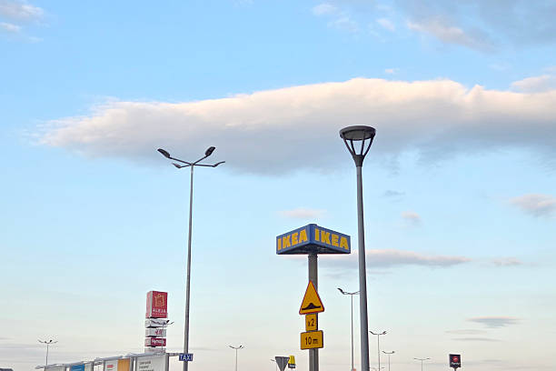 Wroclaw, Poland, June 28, 2025: Urban scene featuring ikea signage amidst tall lamp posts under a vibrant blue sky. the composition includes various commercial signs set against the backdrop of scattered clouds, emphasizing a mix of commercial and urban elements.