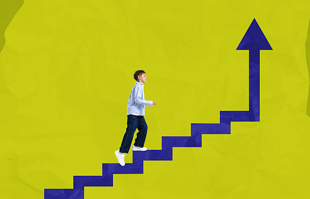 istock Kid climbing upward steps shaped like an arrow symbolizing progr 2250677633