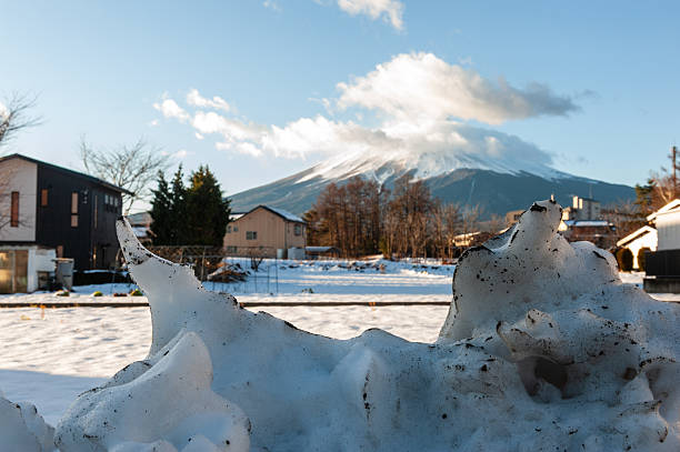 Fujikawaguchiko, Japan - December 26, 2019. Outdoor scene showing a residential area in the Japanese town of Kawaguchiko, with mount Fuji being prominent in the background. It is winter in this snowy landscape.