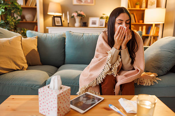 istock Sick woman having flu blowing nose using paper tissues while having online doctor's appointment 2250681062