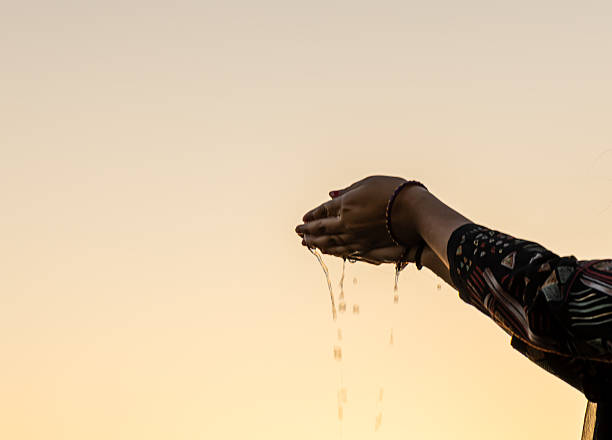 sacred water offering captured as droplets fall from cupped hands