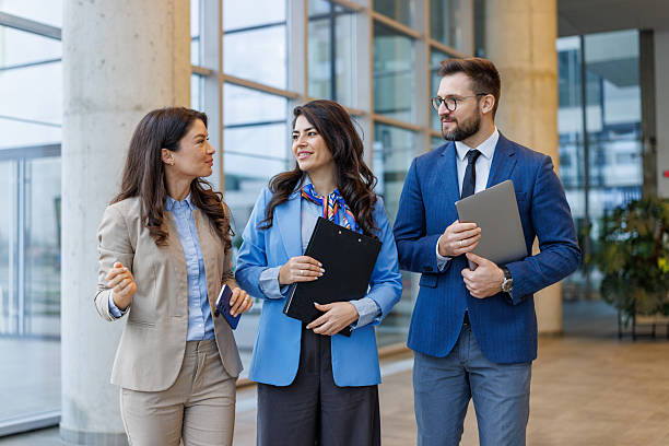 istock Business colleagues walking and talking in modern office lobby 2250683242
