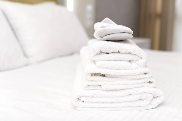istock Neatly arranged white towels on a freshly made bed in a cozy room setting 2250683799