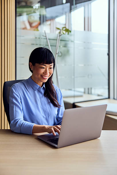 istock Asian Woman Working on Laptop in Modern Office, Smiling While Focused on Work Tasks 2250684186