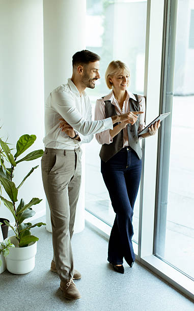 istock Professionals discussing project details by the window in modern office environment 2250684745