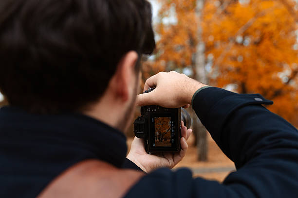 istock Photographer Capturing Autumn Scene with Camera 2250690512