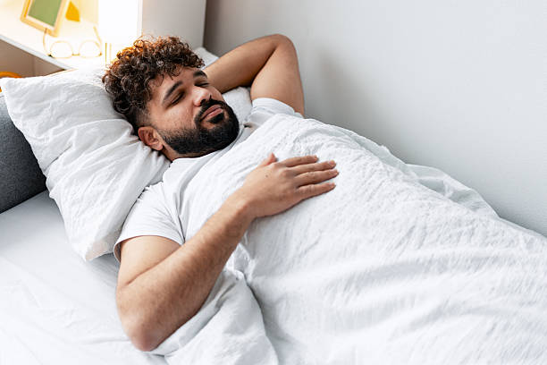 istock Young man sleeping soundly in a comfortable white bed, getting good rest 2250694295