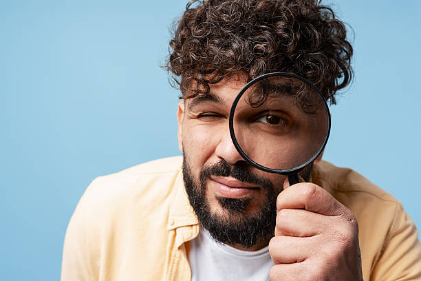 istock Man closely observing with a magnifying glass, winking, searching for details 2250694348