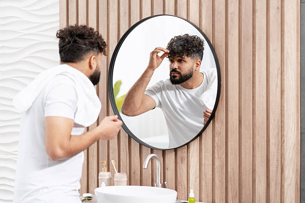 istock Man styling curly hair in bathroom mirror during daily morning routine 2250694376