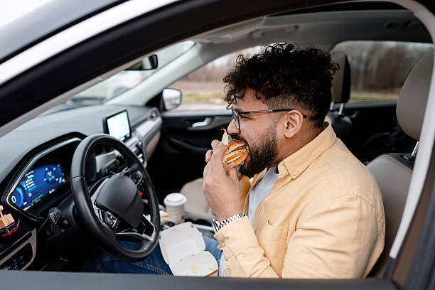 istock Man eating fast food burger in car during a lunch break 2250694454