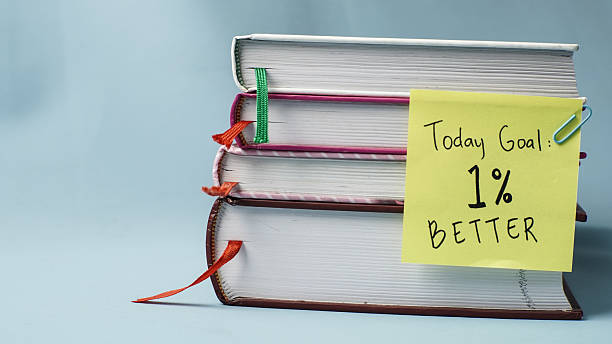 istock Horizontal stack of books with a 1% better motivational sticky note on blue background 2250695529