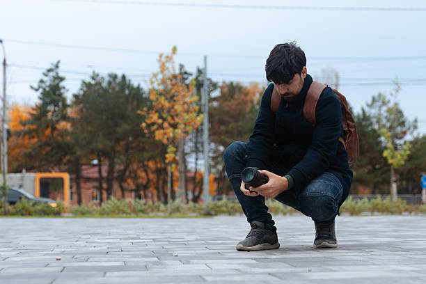 A person with a camera taking photos in a park during autumn, surrounded by colorful foliage.