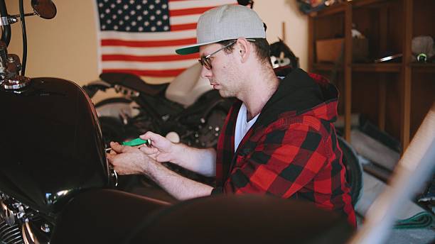 istock Mechanic working on a motorcycle in a garage while an American flag hangs in the background during a bright afternoon 2250699246
