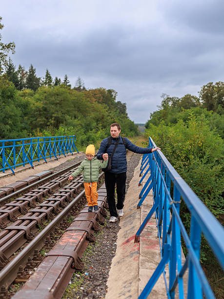 istock A father walks with a child in bright clothes along a metal railway bridge with open copy space. Concept of family safety, guidance, bonding and outdoor walk. 2250701005