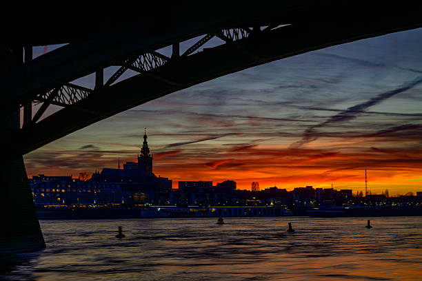 Skyline of the city Nijmegen on the riverbank of the Waal seen from the Waalbrug during sunset. Various ships are passing the river during this beautiful cold winter sunset during the blue hour at the end of the day.