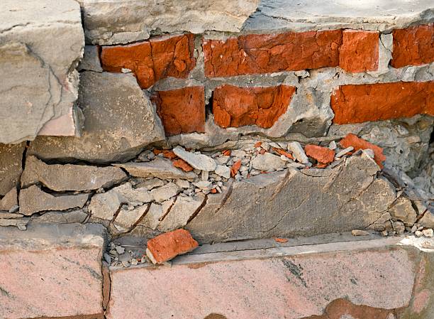 istock A close-up of a severely damaged brick wall reveals exposed red bricks amidst crumbling, cracked grey mortar and concrete debris. 2250702849