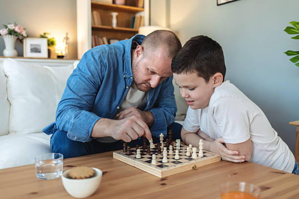 istock Playing, bonding and father with child for chess in home for learning, development or competition. Teaching, smile and dad with boy kid for board game with checkmate for problem solving skills. 2250705234