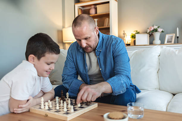 istock Playing, bonding and father with child for chess in home for learning, development or competition. Teaching, smile and dad with boy kid for board game with checkmate for problem solving skills. 2250705236
