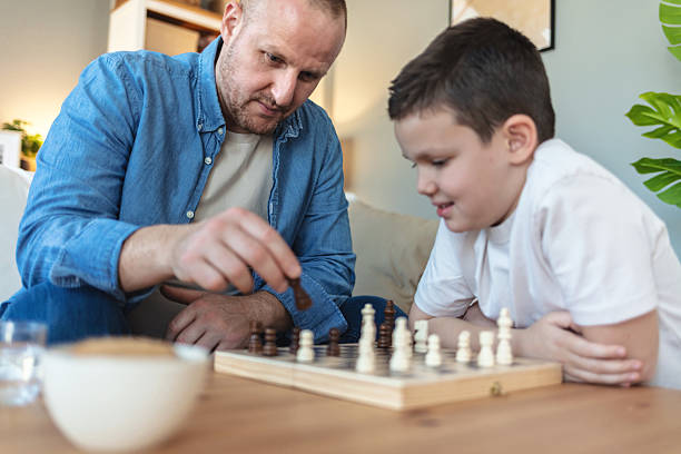 istock Playing, hands and father with kid for chess in home for learning, development or bonding. Teaching, competition and dad with boy child for board game with checkmate for problem solving skills. 2250705238