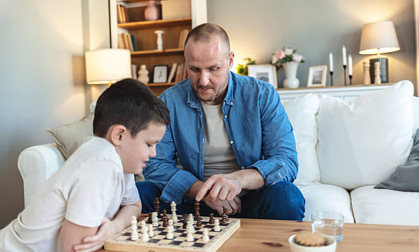istock Playing, thinking and father with child for chess in home for learning, development or bonding. Teaching, competition and dad with boy kid for board game with checkmate for problem solving skills. 2250705240