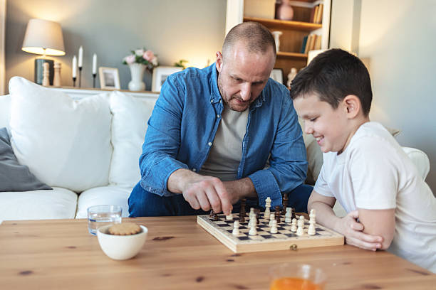 istock Playing, thinking and father with child for chess in home for learning, development or bonding. Teaching, competition and dad with boy kid for board game with checkmate for problem solving skills. 2250705242